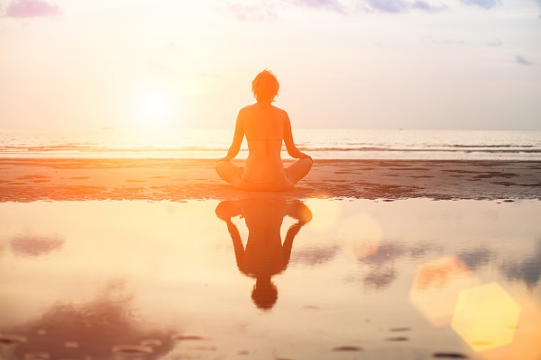 Person meditating in front of a sunrise